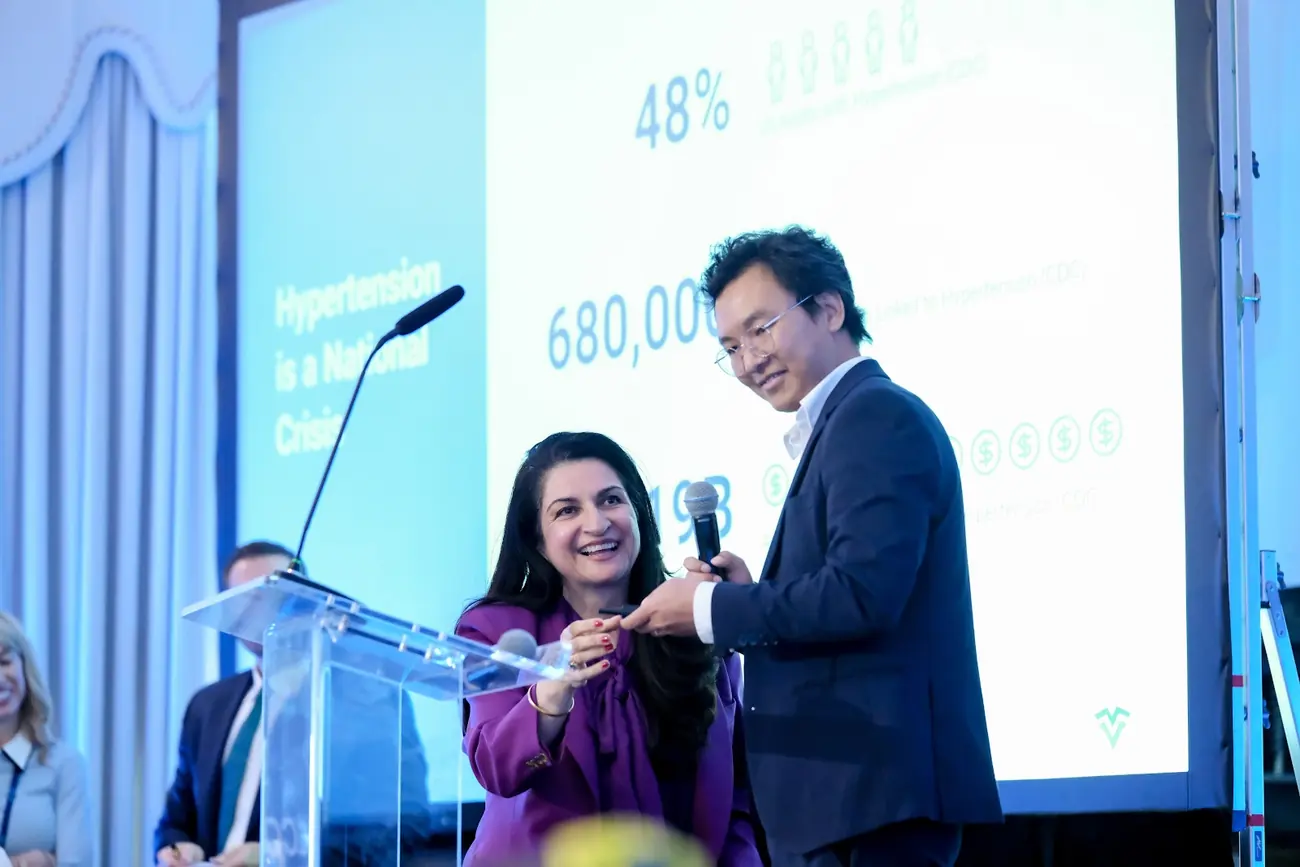 A founder and the host on stage in front of the slides